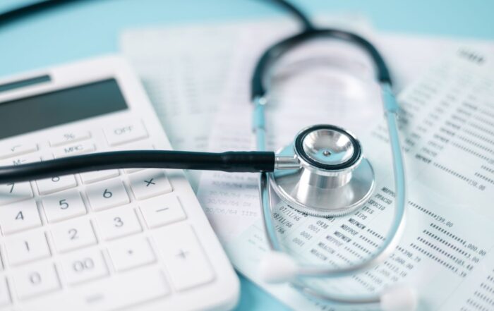 Stethoscope laying near calculator and insurance forms for medical malpractice